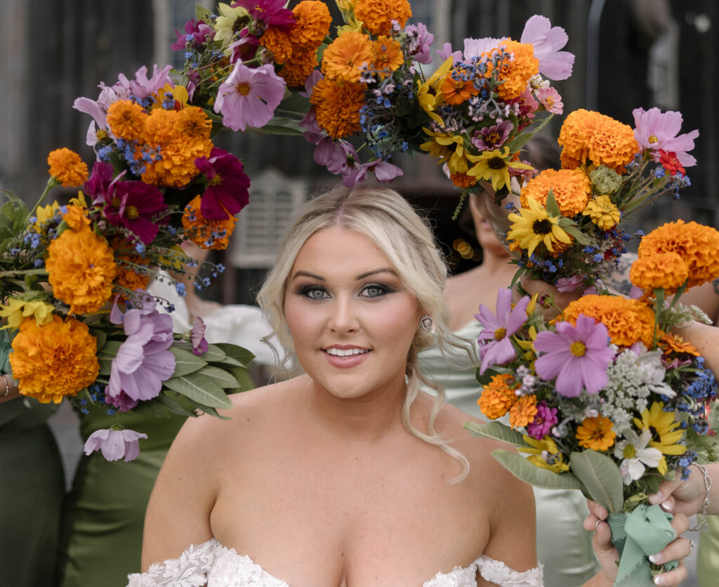 Bride smiling in front of a vibrant floral backdrop at the 1885 Barn in Ohio, captured by a Cleveland-based wedding photographer.