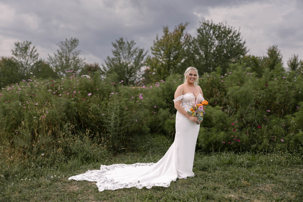 Bride holding her bouquet with her dress train flowing behind her at the 1885 Barn in Ohio, captured by Cleveland-based wedding photographer.”