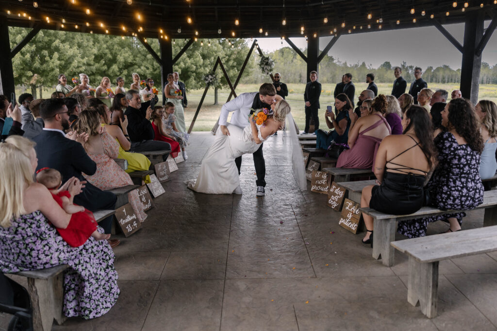 Bride and groom walking down the aisle under a pavilion surrounded by guests at the 1885 Barn in Ohio, captured by Cleveland-based wedding photographer