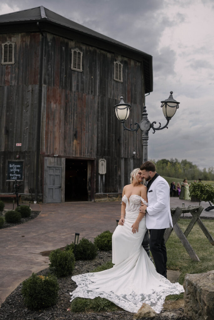 bride and groom sharing a kiss in front of a barn