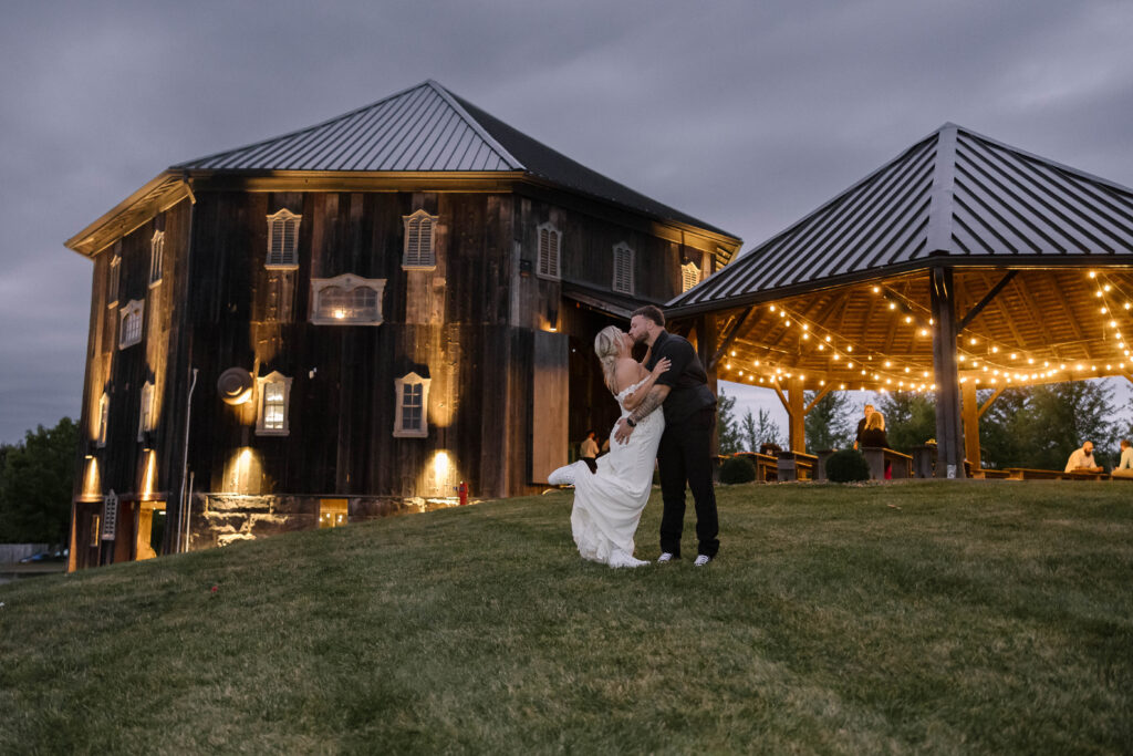 Bride and groom love in front of barn at sunset