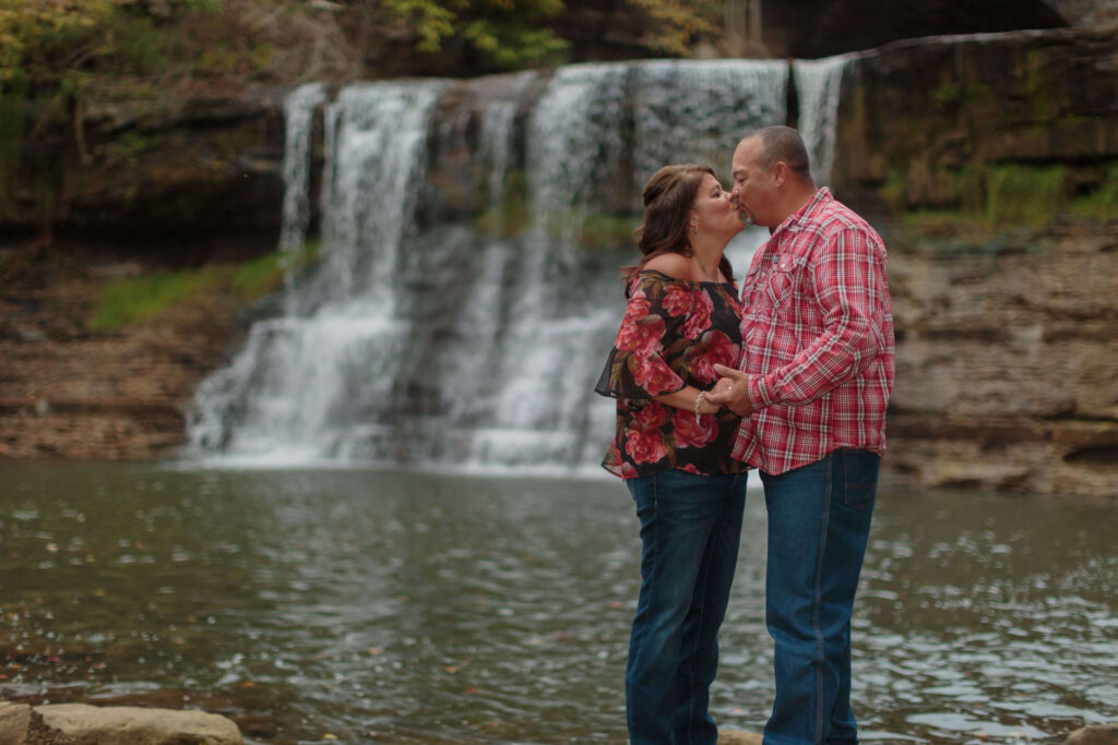 Romantic moment of a couple kissing near the iconic waterfall at Chagrin Falls during their engagement photo session