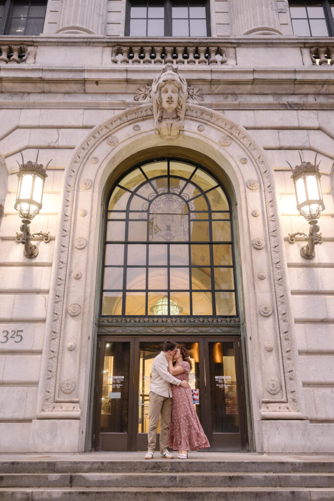 Romantic engagement photo of a couple standing in front of the grand entrance of the Old Arcade in Cleveland.



