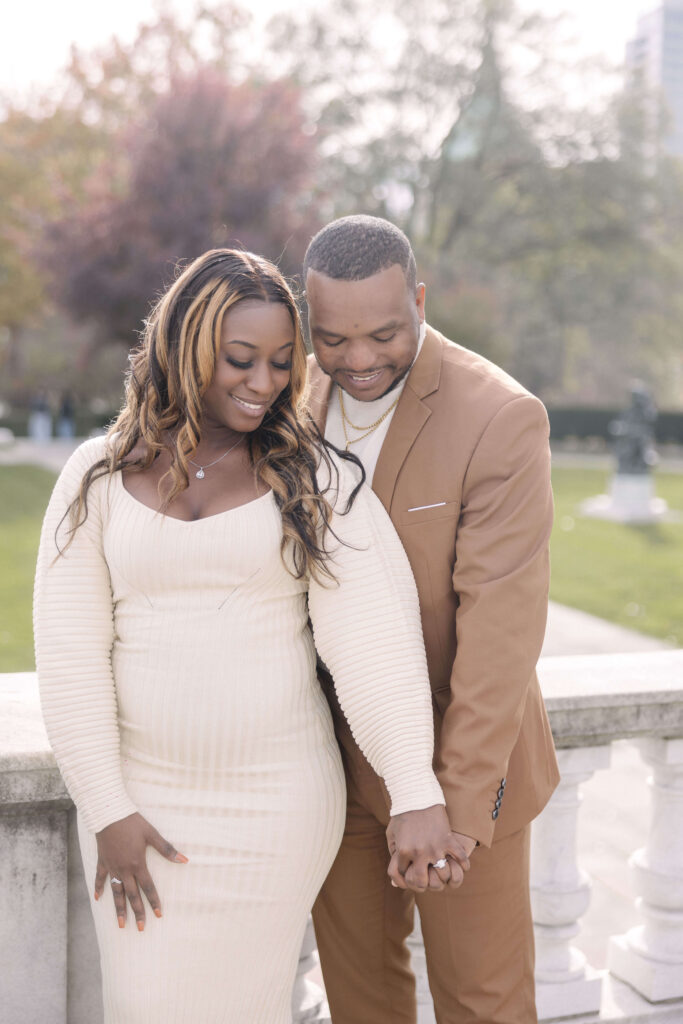 Romantic engagement photo of a couple embracing near the Cleveland Museum of Art with fall foliage in the background.