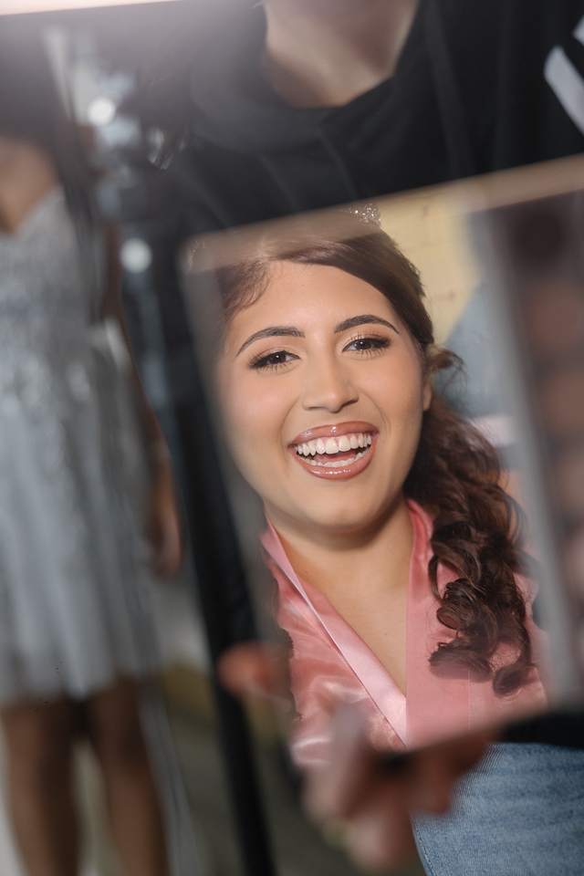 Yariana smiling in a mirror during her quinceañera preparations.