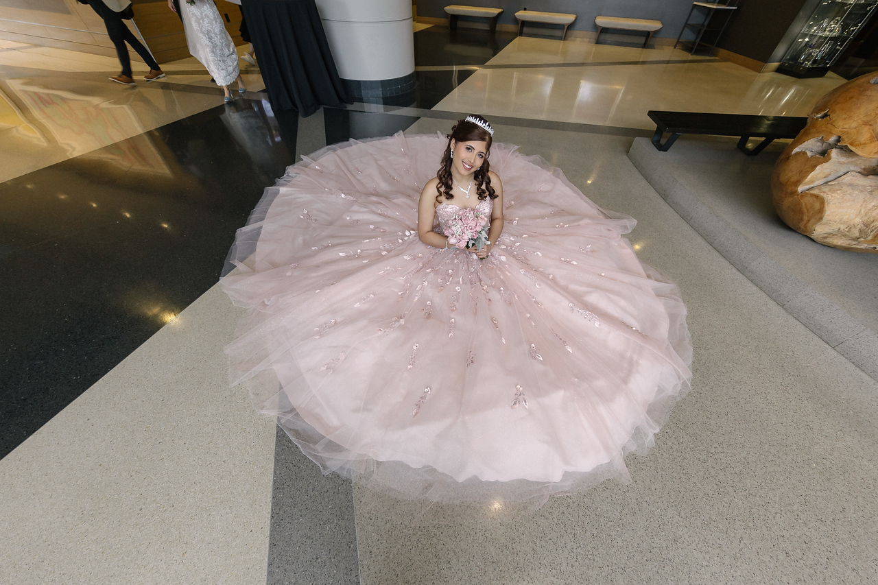 Overhead portrait of Yariana with her pink gown spread around her in the hotel lobby.