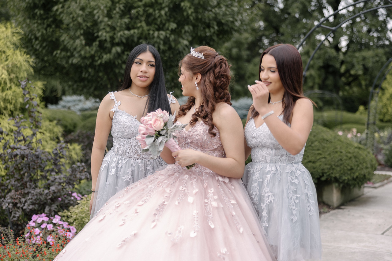 Yariana sharing a candid moment with two companions surrounded by garden flowers.