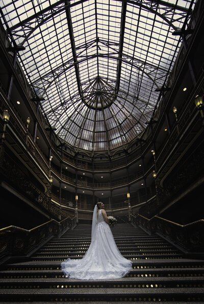 A bride on the grand staircase beneath the glass ceiling of Cleveland’s Old Arcade