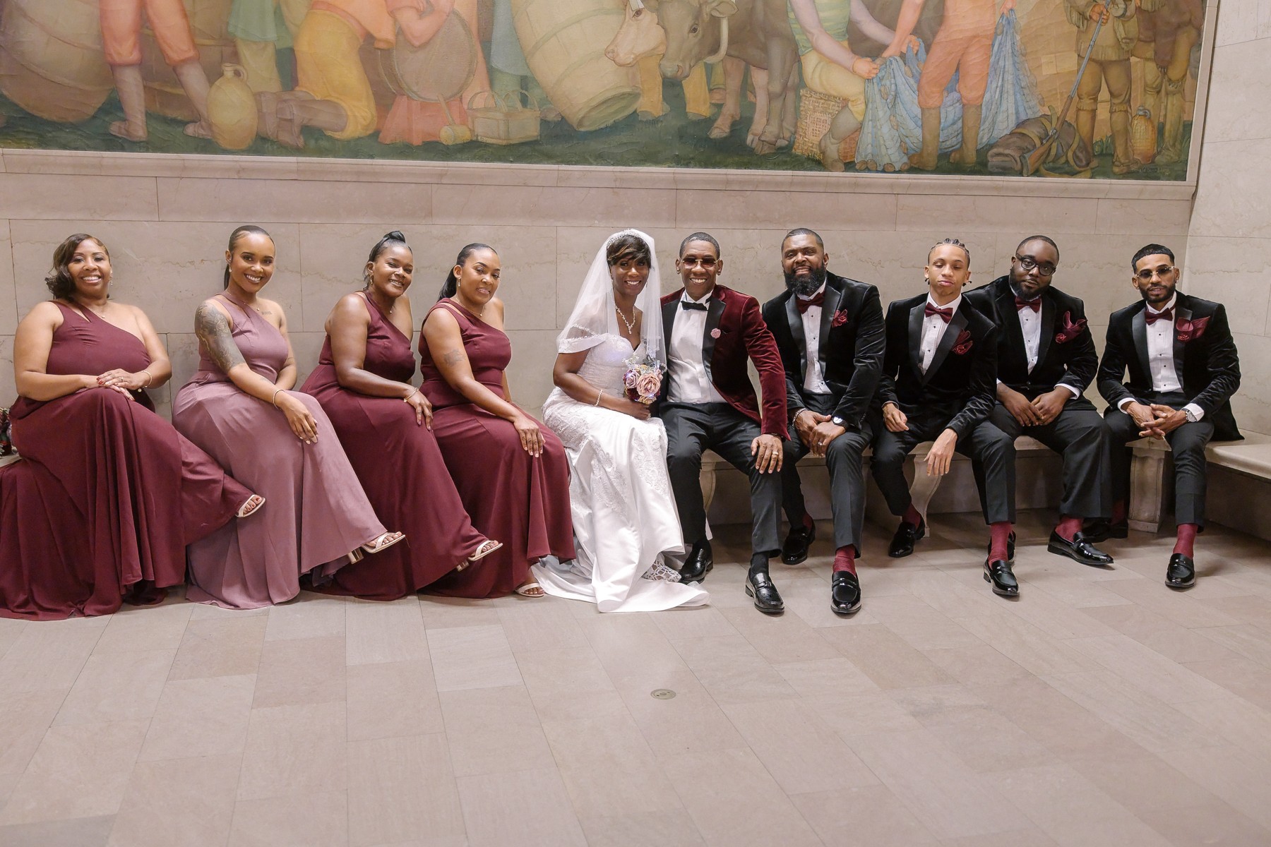 Yolanda and Ron with their wedding party beneath a library mural